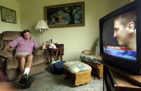 In a 2001 photo, Bill McVeigh, the father of Oklahoma City bomber Timothy McVeigh, pictured on the television, watches from his living room as a news station reports that a federal judge refused to block his son's execution.