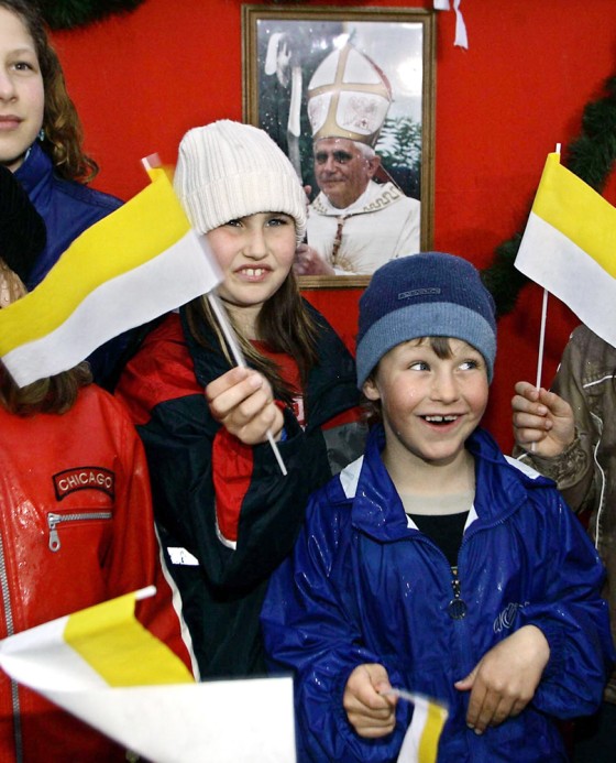Children wave flags in front of a pictur
