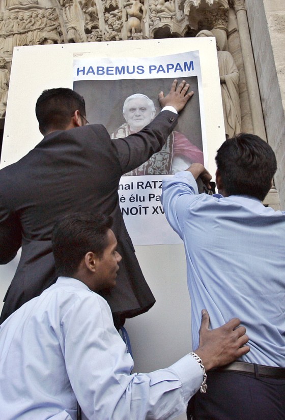 Members of the Paris archdiocese post a poster of the newly-elected Pope Benedict XVI on Tuesday in front of Notre Dame Cathedral, a few hours after his election as the 256th spiritual leader of the Roman Catholic Church.
