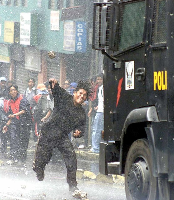 Ecuadorean demonstrators hurl stones towards an anti-riot vehicle during clashes in Quito