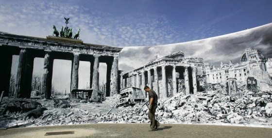A man walks in front of a large photographic print of the destroyed Pariser Platz after World War Two in Berlin