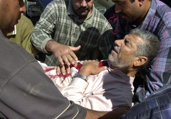 Iraqis help Hameed Shihab, 52, who was wounded when clashes between gunmen and U.S. Army forces erupted at the northern checkpoint in Ramadi, 70 miles west of Baghdad, Iraq, on Tuesday.