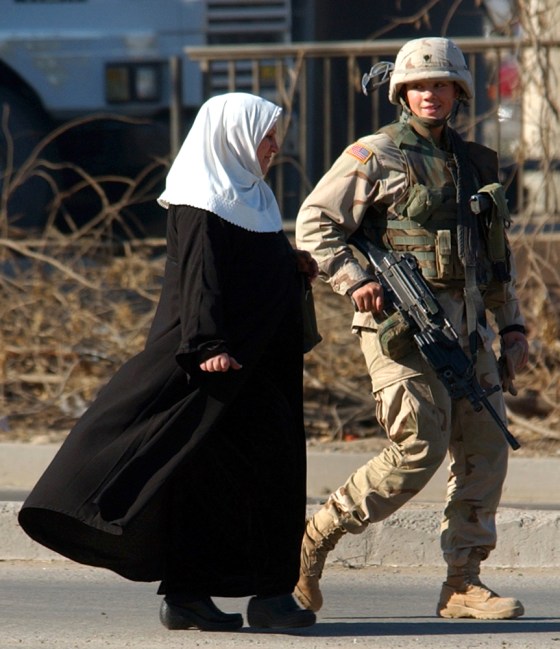 A female American soldier escorts an Iraqi woman away from the scene of a Baghdad suicide car bombing last November. Some 20 percent of U.S. combat support and service roles in Iraq are now filled by women.