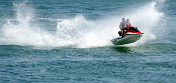 Riders on a personal watercraft roar across the water at the end of South Beach in Miami Beach, Fla.