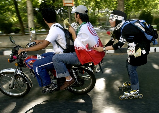 A Rollerblader holds the back of a young boy, both supporters of former Iranian President and presidential candidate Akbar Hashemi Rafsanjani, as they roll through Tehran on June 7.