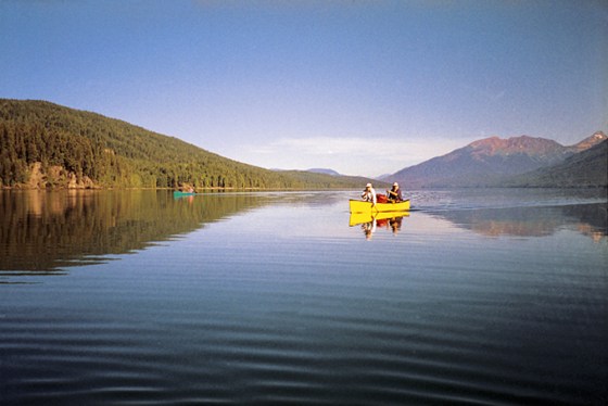 Canoeists slice through the glass-calm waters of Wells Gray Provincial Park.
