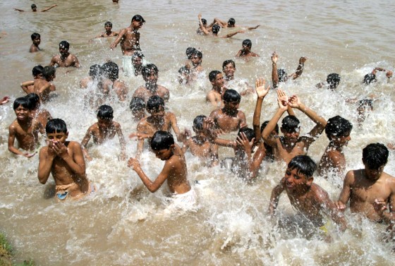 Pakistani youths splash water as they cool themselves on a hot day in Multan