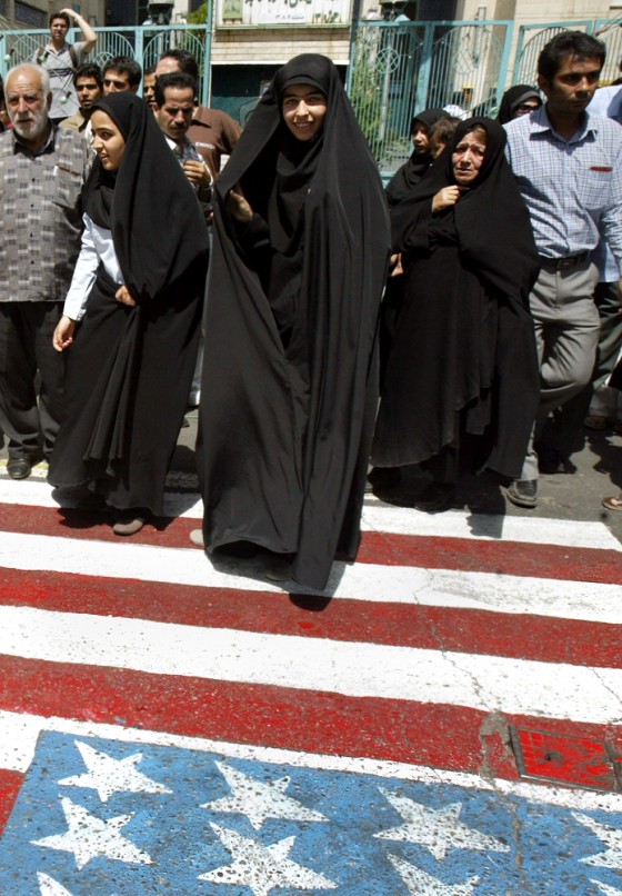 Iranian women walk on a US flag painted