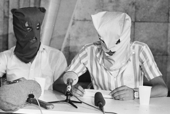 Two hooded Shiite Muslim men, who were identified as hijackers of the TWA jet seized on a flight from Athens to Rome on July 14, 1985, and commandeered to Beirut airport, hold a news conference in the Beirut airport's transit terminal on July 30, the day the standoff ended.