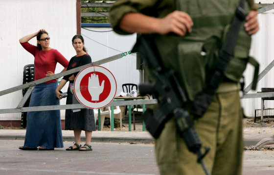 An Israeli soldier stands guard after the area was declared a military zone, as Jewish settler residents look on from the Palm Beach Hotel, also known by extremists as "Fortress by the Sea," near the settlement of Neve Dekalim, in the southern Gaza Strip, on Thursday.