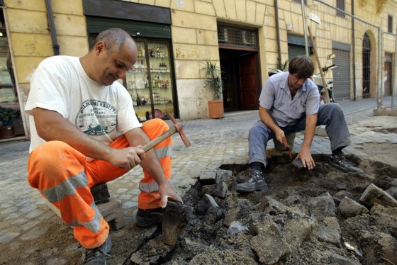 Workers remove cobblestones from a street in Rome, July 22. The ancient stones are costly to lay and maintain.