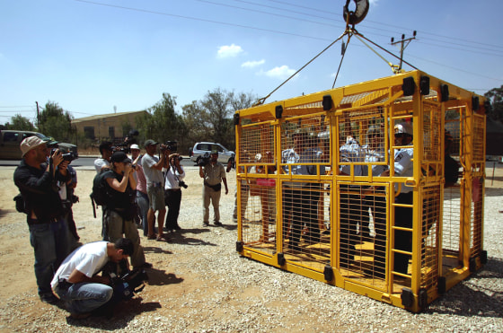 Reporters take pictures Tuesday of Israeli border policemen in a cage to be used during the evacuation of a Jewish settlement, during an exercise at Zeelim military base, in southern Israel.