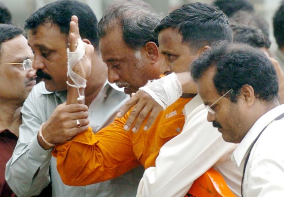 Indian officials escort an injured survi