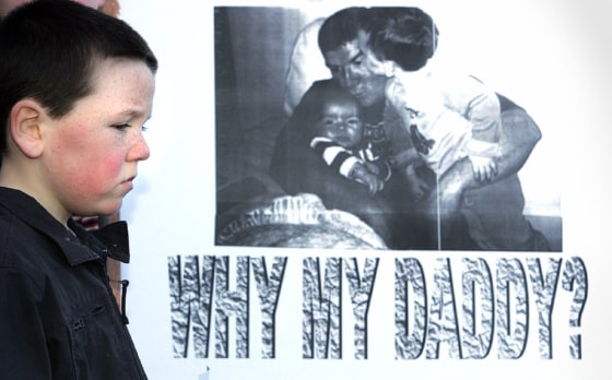 File photo of Declan, nephew of murdered Northern Ireland man Robert McCartney, stands near poster during a mass rally in east Belfast