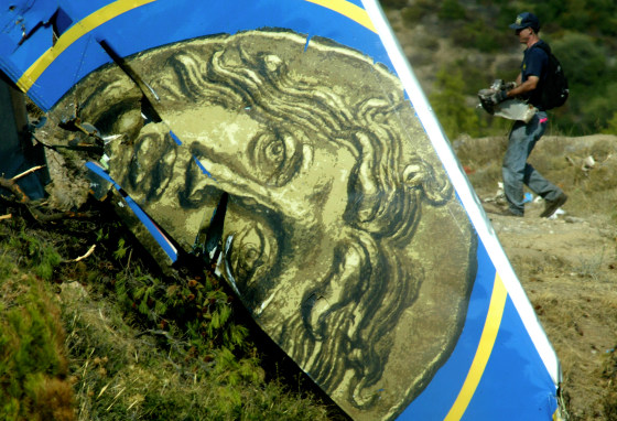 A member of the U.S. National Transportation Safety Board investigators team carries wreckage Wednesday at the site of the Helios plane crash, on the fourth day of investigations.