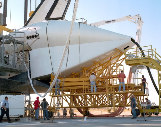 Technicians attach the tail cone to the space shuttle Discovery on Tuesday in preparation for its return to NASA's Kennedy Space Center in Florida.
