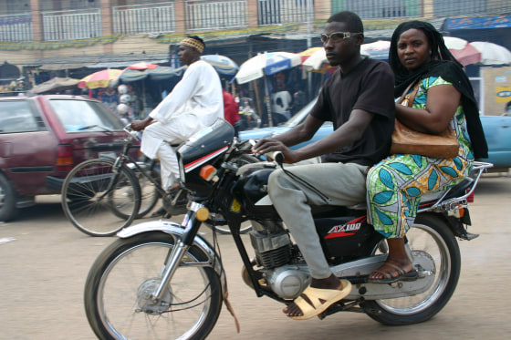 A&nbsp;woman rides a motorcycle taxi in Kano's traffic. Soon, she will be allowed only to use&nbsp;special, woman-only motorcycles.