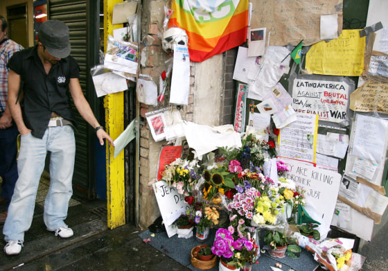 An unidentified member of the public reads a tribute on Wednesday at a makeshift memorial for Brazilian Jean Charles de Menezes, who was mistakenly shot dead by police at Stockwell Underground station, in London.
