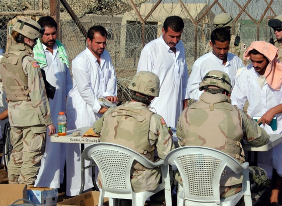 Former detainees wait their turns at sign-out table as US Army soldiers process them out of Abu Ghraib prison in Baghdad