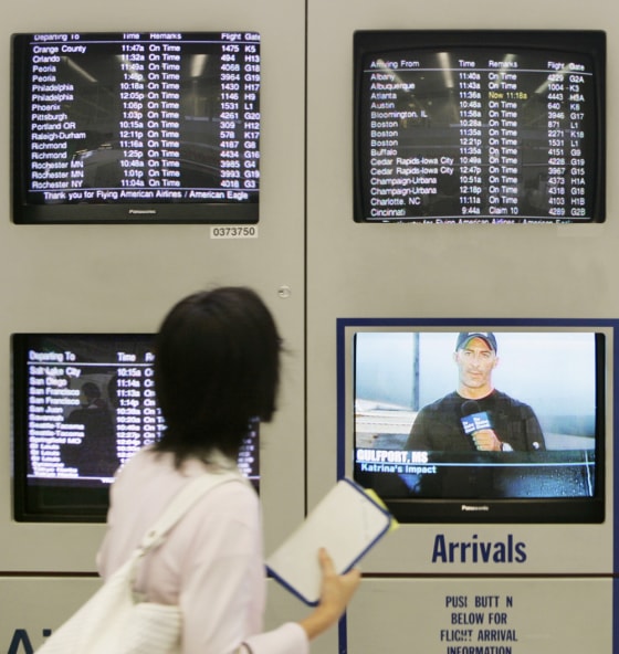A traveler checks the departure monitors for any delays or cancellations at the American Airlines terminal at Chicago's O'Hare International Airport Tuesday as another monitor airs a broadcast of the storm's impact to states along the Gulf Coast.