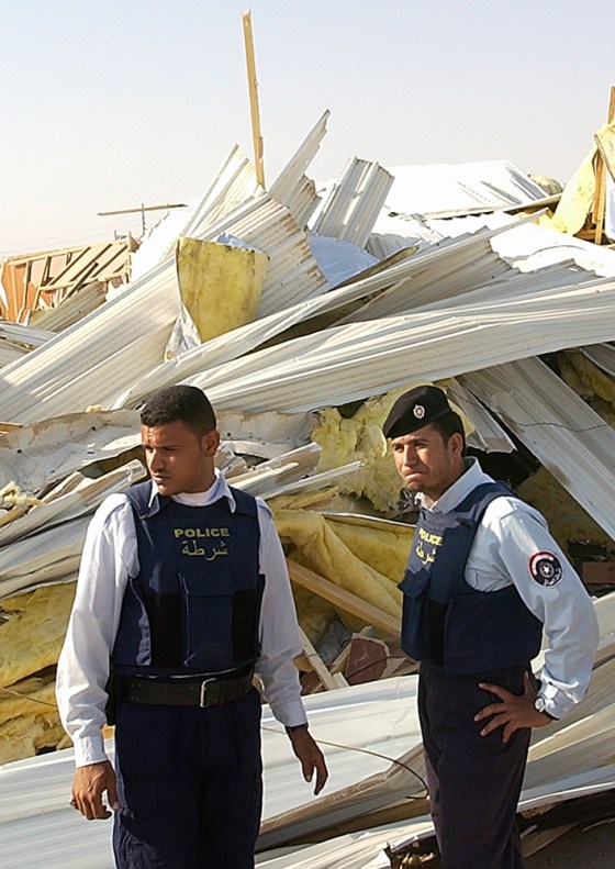 Iraqi police officers stand near debris at the central jail in Basra, Iraq, on Tuesday. British armored vehicles broke down the walls of the jail to free two British soldiers, arrested for shooting two Iraqi policemen. The men were later found to be held by militants in another location.