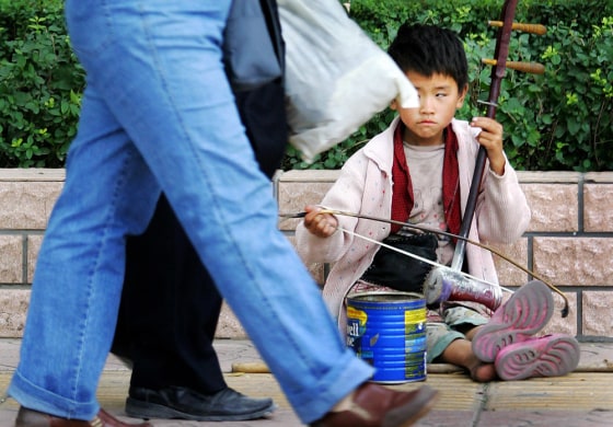 Pedestrians walk past a child playing a