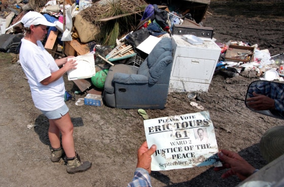 Eric Toup's sister, Darlene Montet, left, hands Eric his election poster from 1996 which she rescued from her flooded Henry, La., home.