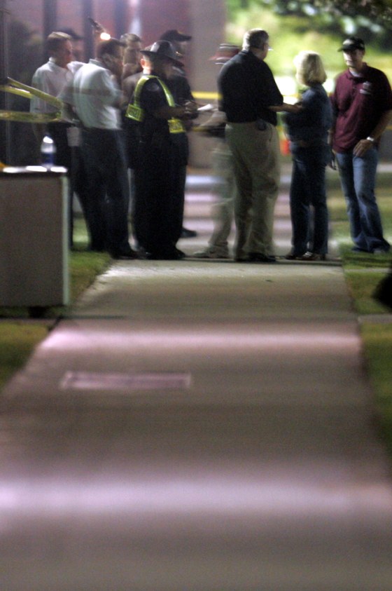Officials mill around inside the police perimeter after one person was killed by an explosion near a packed football stadium at the University of Oklahoma on Saturday.