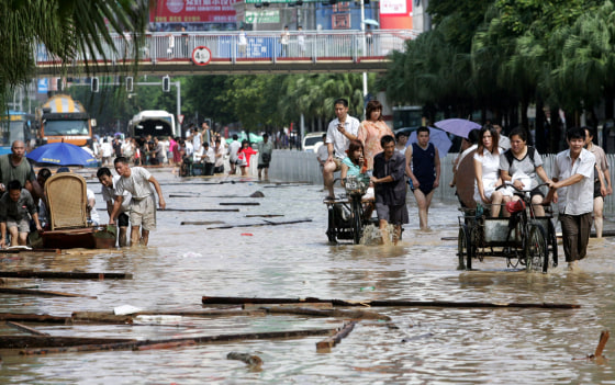 Chinese make their way in the flooded city centre of Fuzhou in Fujian province, eastern China