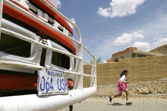 A Bolivian student runs past Monica Lozada's family's house in the city of Cochabamba, Bolivia, on Thursday. The woman's relatives are stunned by word of her killing, and are anxious to resolve a dispute over who should adopt Lozada's 4-year-old daughter.
