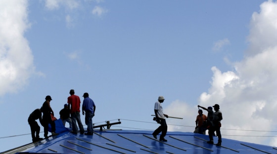 Construction workers with the Rabren General Contractors of Auburn, Ala., place a temporary plastic cover on a duplex home on Gadsen Street in Kenner, La., just outside New Orleans.