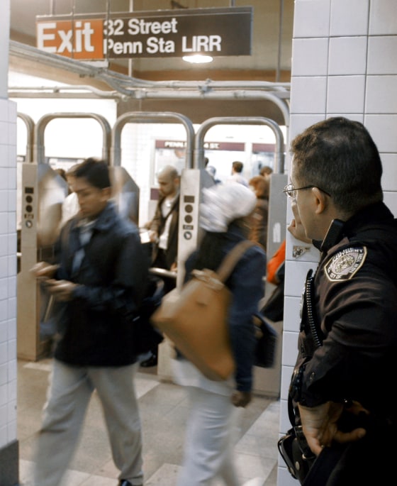 A New York City police officer observes people passing through Penn Station on Tuesday. After four days on high alert, police announced Monday they were scaling back security measures in the subways because no evidence had emerged that an alleged terrorist plot would be carried out.