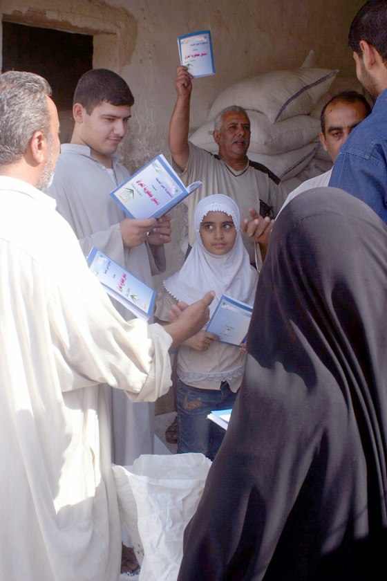Iraqis receive copies of Iraq's new constitution during food rations distribution in Najaf