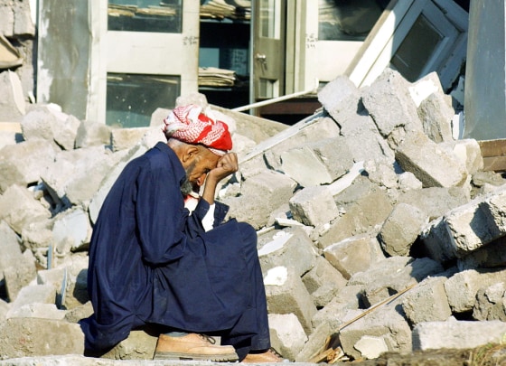 An earthquake victim sits in front of hi