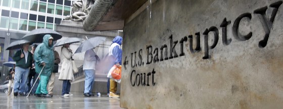 People wait in line under umbrellas against the rain outside U.S. Bankruptcy Court in New York on Friday. Thousands of consumers across the nation filed bankruptcy petitions Friday to beat the start of a new federal law that sets stricter standards for seeking protection from creditors.