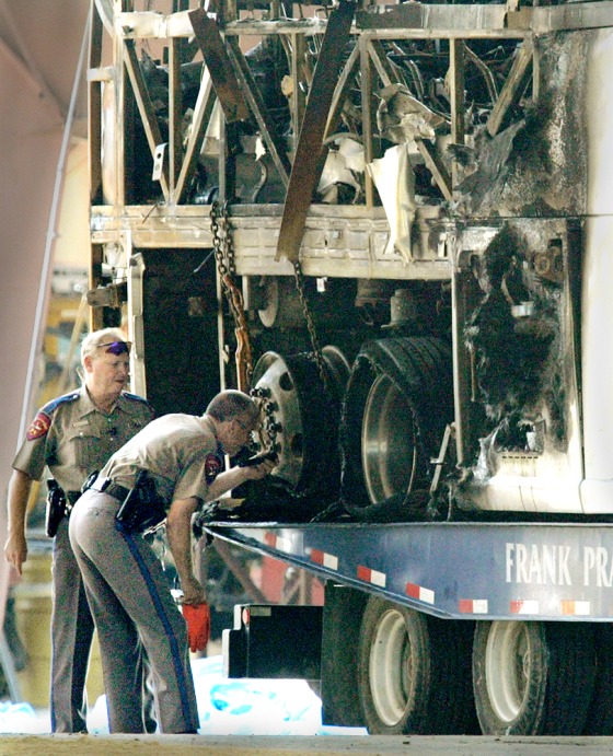 Texas highway patrol officers examine the back wheels of a bus that caught fire and exploded, killing 23 elderly Hurricane Rita evacuees, Sept. 23, 2005 in Wilmer, Texas.