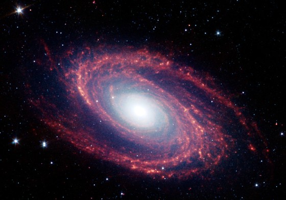 NASA's Spitzer Space Telescope captured this image of the spiral galaxy M81, located 12 million light years from Earth. The infrared radiation emitted by nitrogen-containing polycyclic aromatic hydrocarbon molecules is shown in red. 