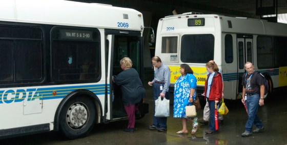 Commuters board a bus at the Empire State Plaza in Albany, N.Y. Mass transit systems nationwide are considering cutting services, staff, or raising fares and delaying spending to meet fuel costs.