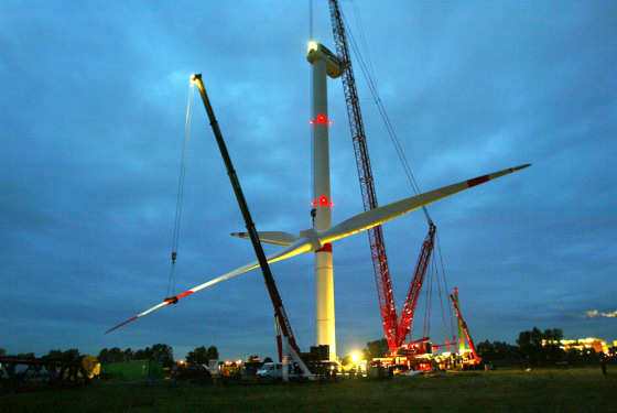 Cranes lift up the rotor of a giant wind generator near Hamburg