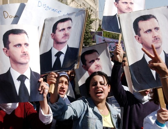 Syrian women hold posters showing President Bashar Assad as they demonstrate in Damascus on Monday, to protest against the U.N. report on the assassination of former Lebanese Prime Minister Rafiq Hariri that implicated Syrian and Lebanese officials.