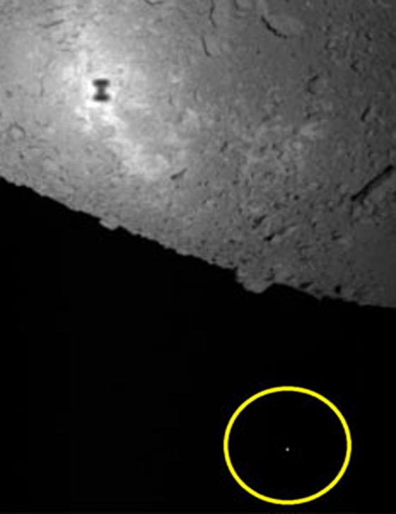 In this photo, taken by the Hayabusa mothership, the object within the yellow circle is thought to be the MINERVA mini-robot, floating in space. Hayabusa's shadow can be seen on the surface of asteroid Itokawa, toward the top of the frame.