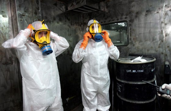 Two technicians adjust protective wear next to a box containing uranium ore concentrate at the Uranium Conversion Facility of Iran near Isfahan in this August file photo. Iran is said to have resumed processing activities there.