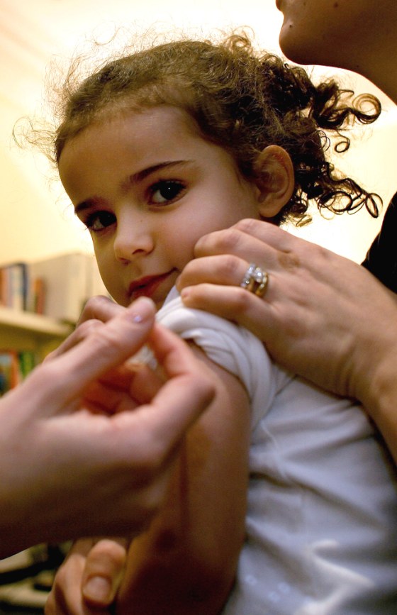 Nurse injects Asia Pesaro with the flu vaccine at a clinic in central London