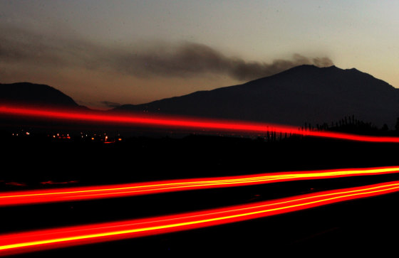 A vehicle passes along a highway as smoke is emitted from the Galeras volcano in Chachagui