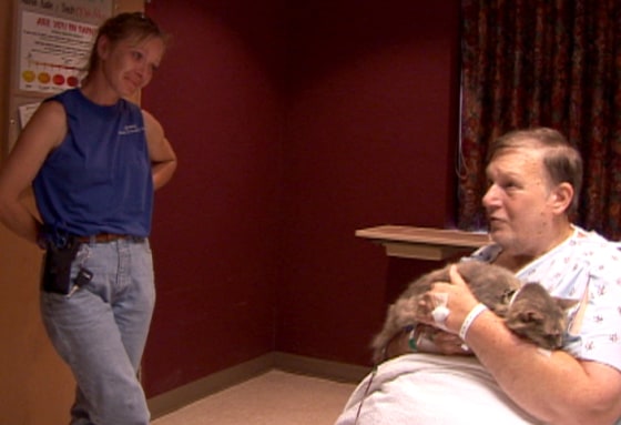 Donna Wackerbauer, left, watches as the late Bill Harris cradles Miss Kitty during the pair’s reunion in a Hattiesburg, Miss., hospital Sept. 9.