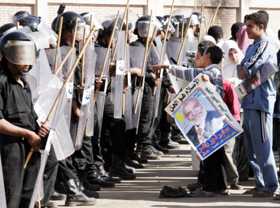 Egyptian supporters of the Islamic party, the Muslim Brotherhood, hold a poster of candidate Saber Nour as anti-riot police block the entrance to a polling station in Al Mansoura, north of Cairo, on Thursday.