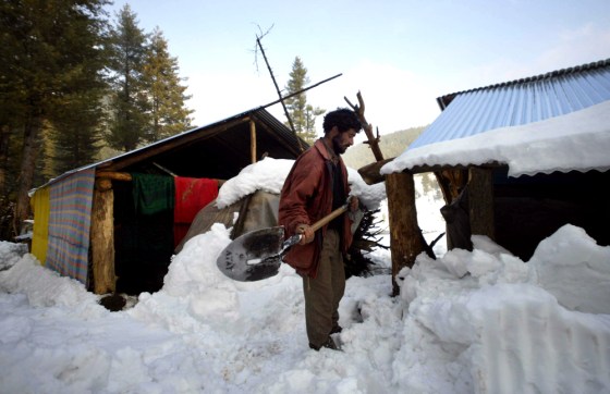 Uness Khan, a earthquake survivor clears snow from his temporary shelter in Drangyari, north of Srinagar, India, on Thursday. Worsening weather has severely hampered aid efforts in earthquake-ravaged northern Pakistan.