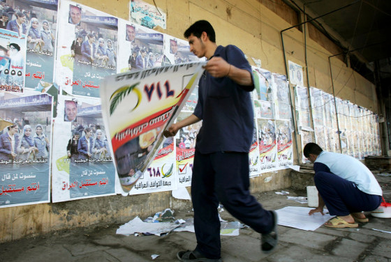 Iraqi men hang election posters on street in Baghdad