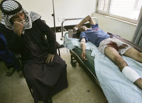 Man sits with his wounded son after attack on training academy in Baghdad
