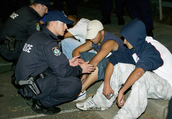 Police (L) watch over detained youths (R